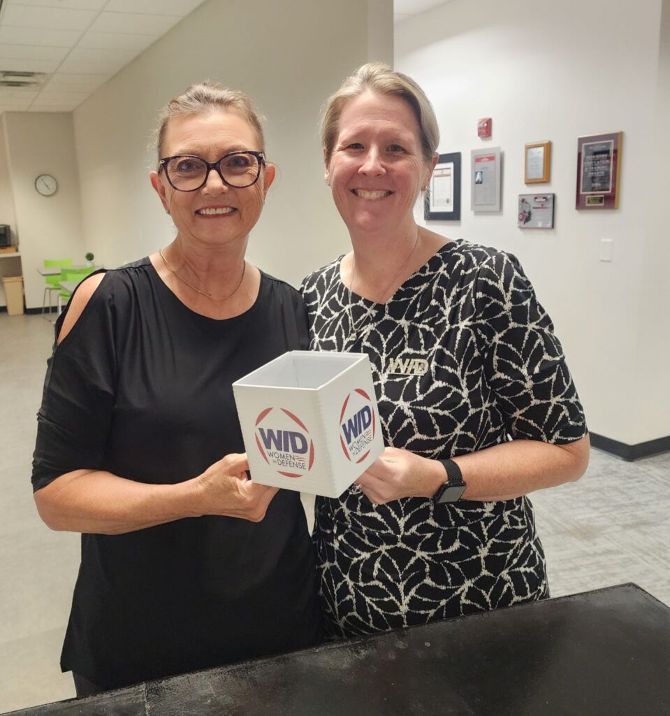 Two WID members smile and hold up a WID logo box