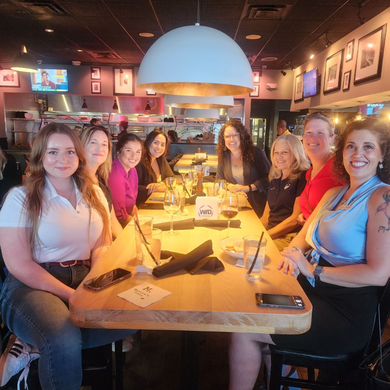 Several WID Central Florida chapter members smile during a networking dinner.